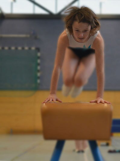 Mädchen springt über eine Bock im Sportunterricht