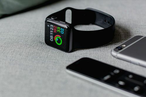 Smartwatch und Smartphone auf einem grauen Untergrund
