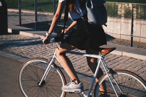 Frau mit schwarzem Rock, die auf einem weißen Fahrrad fährt